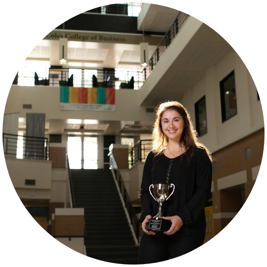 [image] a student holding a trophy in the Coles building on the Kennesaw campus